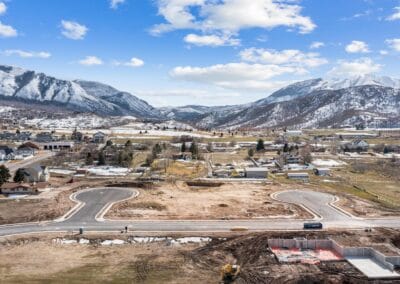 An aerial view of a construction site with mountains in the background in Southern Utah Valley, where Riding Homes, a custom home builder, is at work.