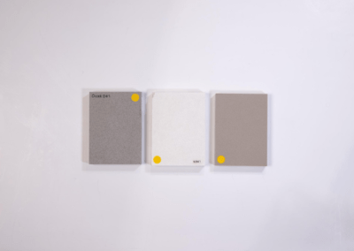A white wall adorned with three stylish and vibrant phone cases featuring shades of grey and yellow.